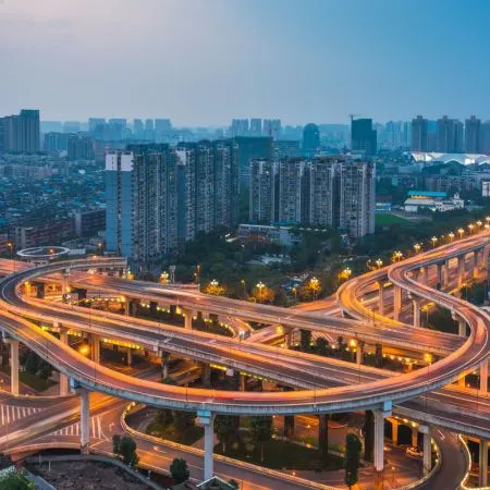Noida Real Estate Urban Infrastructure Multi-level highway interchange with illuminated roads and high-rise buildings in Noida real estate skyline.