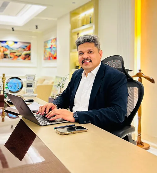 Rajesh Kumar, Director of Mega Realtymax, sitting at his desk in a modern office.