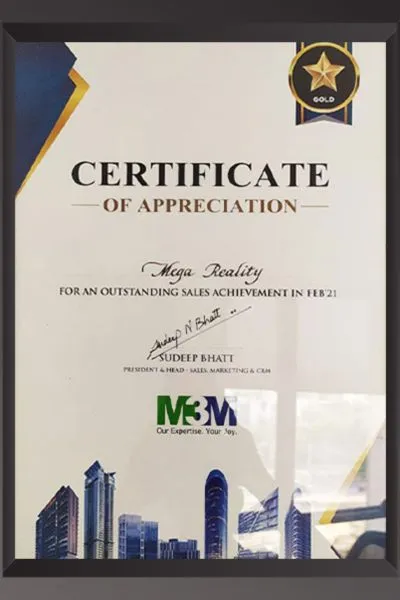 A white framed Certificate of Appreciation with a Gold Star badge from M3M, awarded to Mega Realty for outstanding sales achievement in February 2021. Signed by Sudeep Bhatt, President & Head – Sales, Marketing & CRM, with M3M branding and building imagery at the bottom.