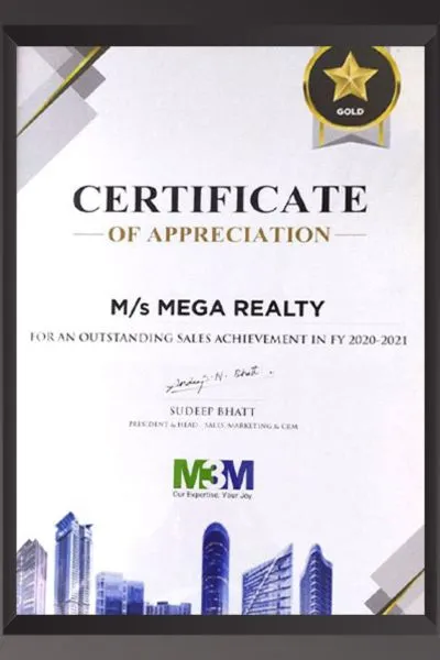 A white framed Certificate of Appreciation with a Gold Star badge from M3M, awarded to M/s Mega Realty for outstanding sales achievement in FY 2020-2021. Signed by Sudeep Bhatt, President & Head – Sales, Marketing & CRM, with M3M logo and building imagery at the bottom.