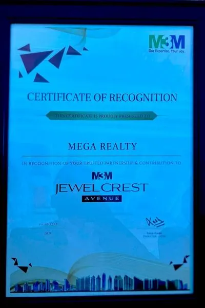 A blue-themed framed Certificate of Recognition from M3M presented to Mega Realty in recognition of their trusted partnership and contribution to M3M Jewel Crest Avenue, with M3M branding and a cityscape graphic at the bottom..