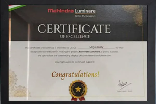A white framed Certificate of Appreciation from Ashiana Anmol (Kid Centric Homes) recognizing Mega Realty as "Most Promising Channel Partner," dated 29/09/2021. Signed by Mr. Abhijit Joshi, Vice President, Gurgaon, with Ashiana branding in red and gold.