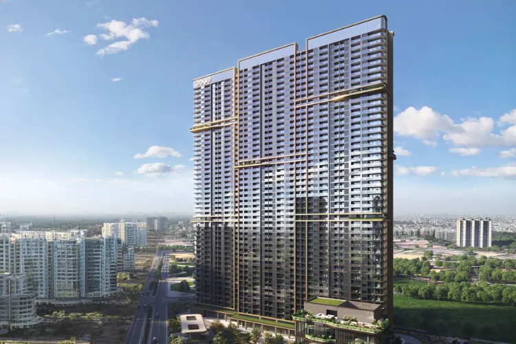  A sunny, daytime architectural rendering of the BPTP Amstoria Verti Greens high-rise building. The tall, modern tower has a distinctive two-toned facade, with a darker lower section and a lighter, more reflective glass upper section, featuring a unique roofline design. The building is shown in an urban setting with a wide road, other high-rises, and green spaces in the background under a partly cloudy blue sky.