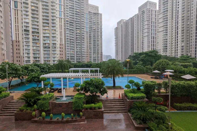 View of DLF Park Place residential towers with a central amenity area featuring a blue sports court, white pergola, and lush green landscaping.