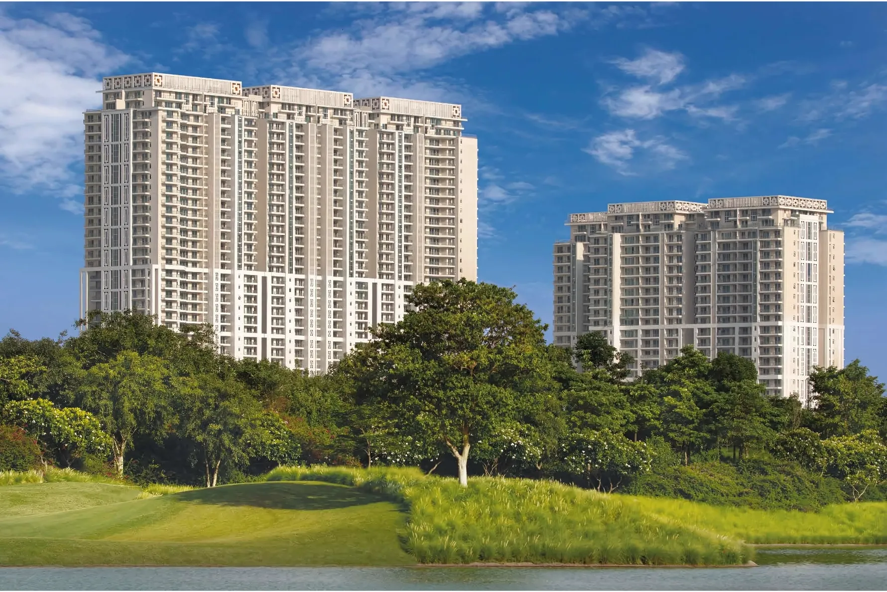 Two modern high-rise residential towers, DLF The Crest, rise above a lush green landscape with trees and a golf course, under a blue sky with white clouds.