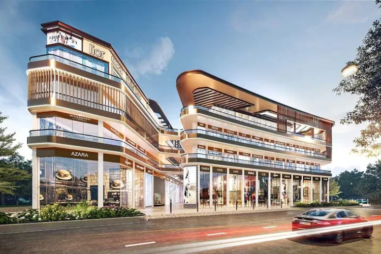  Exterior view of Elan Empire showing a modern multi-story commercial complex with glass storefronts, sleek architectural design, and illuminated elements at dusk.