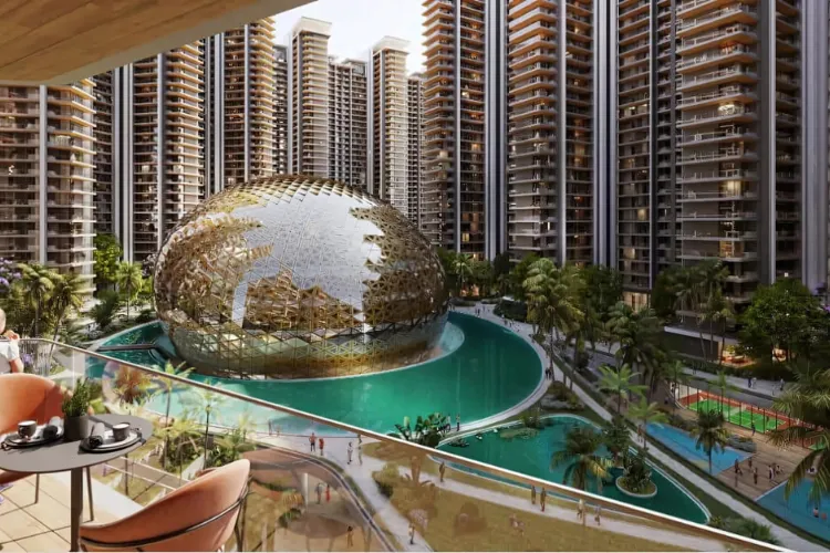  A detailed architectural rendering of Elan The Emperor, showing a massive, geodesic-style golden dome situated in the center of a turquoise-colored water body. The dome is surrounded by a dense cluster of modern residential high-rise towers. The view is taken from a balcony, showing a table and chairs in the foreground, overlooking the central amenity space which also features lush greenery, walking paths, and a sports court.