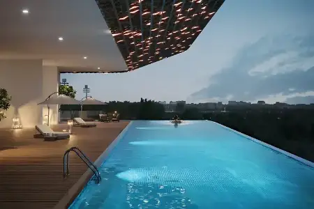 Central Park 104 – Elevated Serenity at Dusk with Infinity Pool Overlooking Gurugram Dusk view of Central Park 104 Gurugram featuring an illuminated covered infinity pool with a single swimmer, deck loungers, and cityscape backdrop