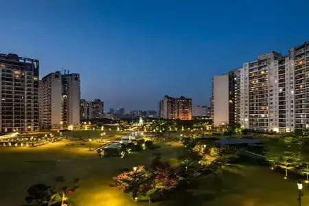 Central Park 104 – Twilight Serenity in Gurugram’s Green Residential Haven Twilight view of Central Park 104 Gurugram featuring high-rise apartments, landscaped gardens, walking paths, and ambient lighting