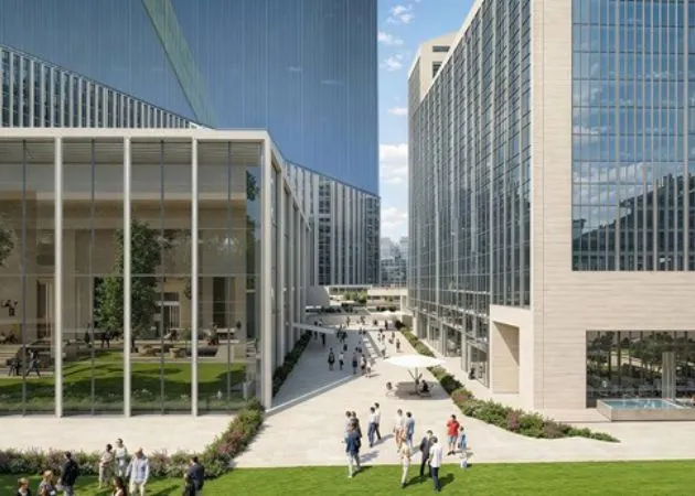 Landmark One Landscaped Courtyard Between Office Towers Landscaped courtyard walkway at Landmark One Sector 67 Gurugram, flanked by glass office towers with a glass atrium building, people walking, a white shade umbrella, and manicured lawns.