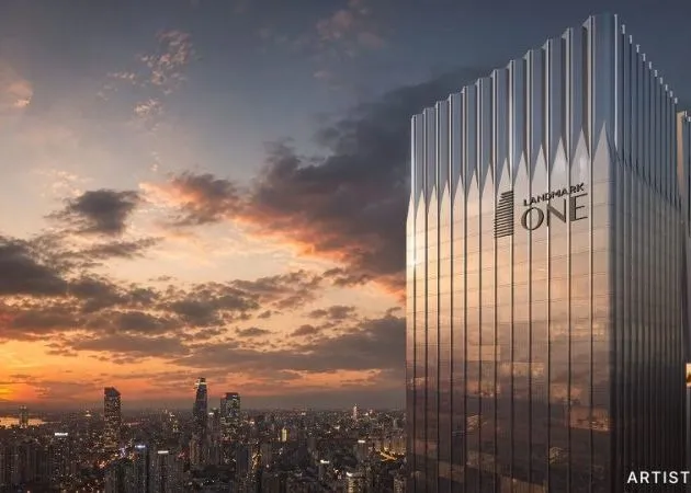 Landmark One Tower Aerial View at Sunset with City Skyline Aerial sunset view of the fluted silver Landmark One tower displaying the "LANDMARK ONE" logo on its facade, overlooking the Gurugram city skyline with an "Artist's impression" label in the corner.