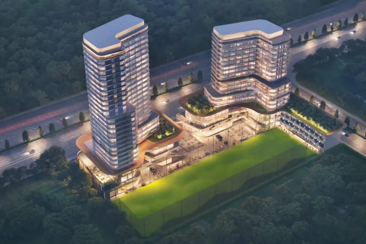 Night view of Central Park Selene Tower at Flower Valley Township, Gurugram featuring twin illuminated high-rise buildings and a landscaped sports field.