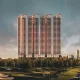 Four sleek, modern residential towers with curved tops and glowing vertical accents, overlooking a lush green golf course under a dramatic sky. The development is M3M Jacob & Co.
