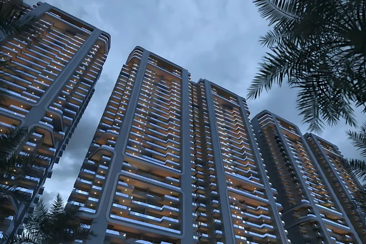 A dramatic, low-angle shot of the SmartWorld One DXP residential towers at night. The multiple modern buildings feature a unique, curved architectural design with numerous balconies, and their windows glow warmly. Dark silhouettes of palm tree fronds are visible in the foreground against a moody, cloudy sky.