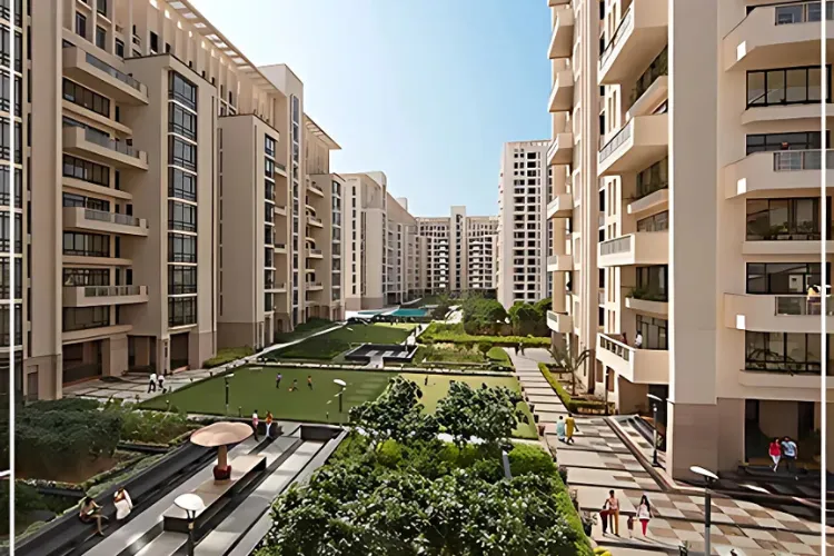 A stunning aerial view of the SS Hibiscus apartment complex in Gurgaon. The image shows several modern residential towers with balconies, surrounding a beautifully landscaped central courtyard. The courtyard features lush green lawns, a swimming pool, and a children's play area. The architecture is contemporary, with clean lines and a light-colored facade. People are visible enjoying the outdoor amenities, suggesting a vibrant community life.