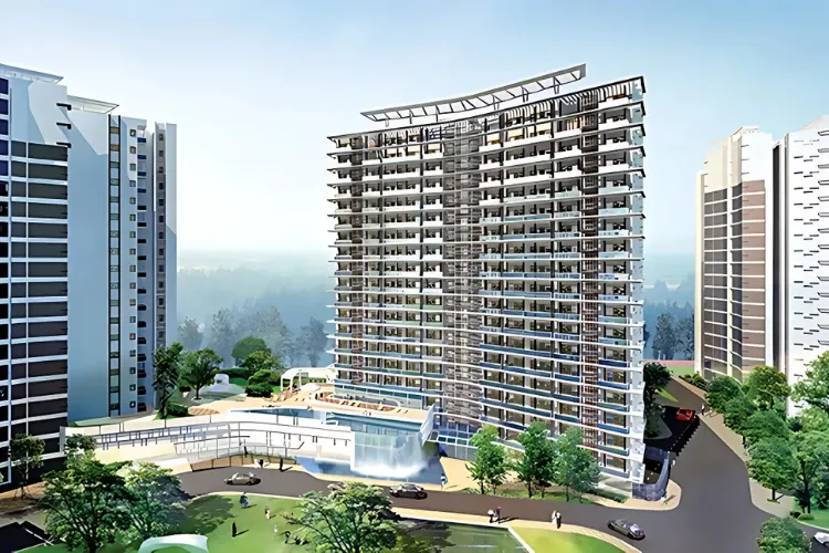 An aerial view of Tata Raisina Residency, a luxury residential complex in Gurugram. The image showcases several modern high-rise towers with contemporary architecture, surrounded by beautifully manicured green spaces, a swimming pool, and other recreational amenities. The complex is set against the backdrop of the Aravalli hills, highlighting its scenic location.