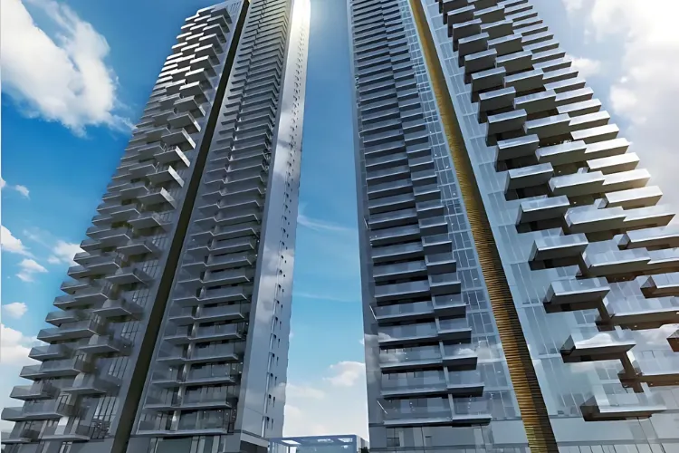 A low-angle shot showcasing the two towering, modern high-rise buildings of Trump Residences Gurugram, with numerous balconies and a bright sky in the background.