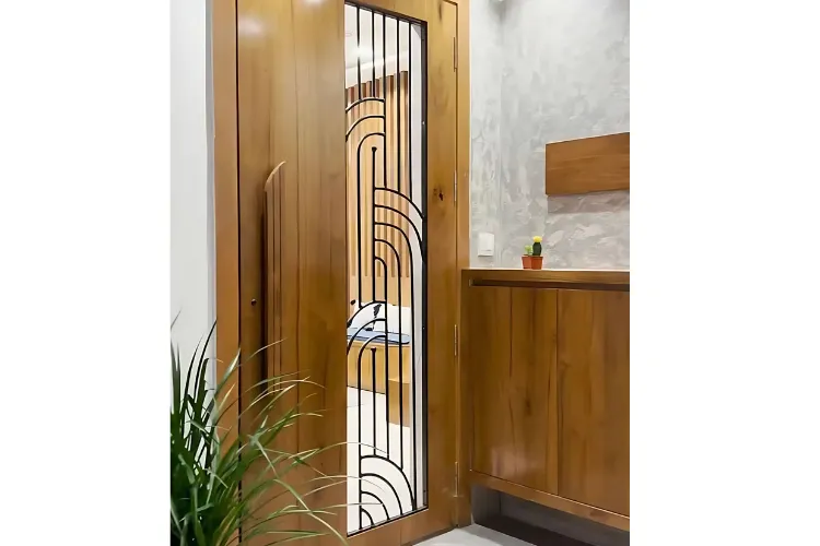 Contemporary wooden bedroom door with a vertical U-shaped metal grill design, placed in a stylish modern interior with matching wooden cabinetry. 