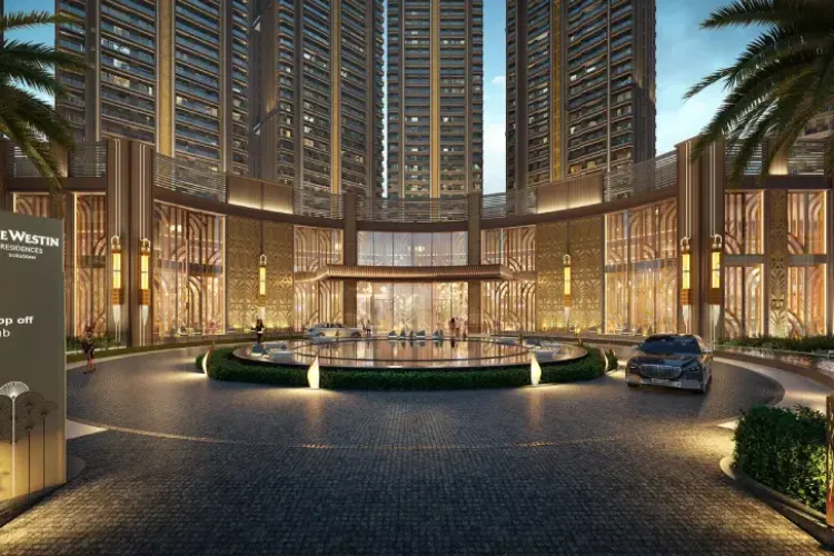  A detailed architectural rendering of the grand entrance to the Whiteland Westin Residences. The image shows a luxurious, circular driveway with a water feature in the center. The entrance building features an opulent facade with intricate patterns, large glass windows, and warm lighting. Tall residential towers are visible in the background, and a car is parked at the drop-off point.